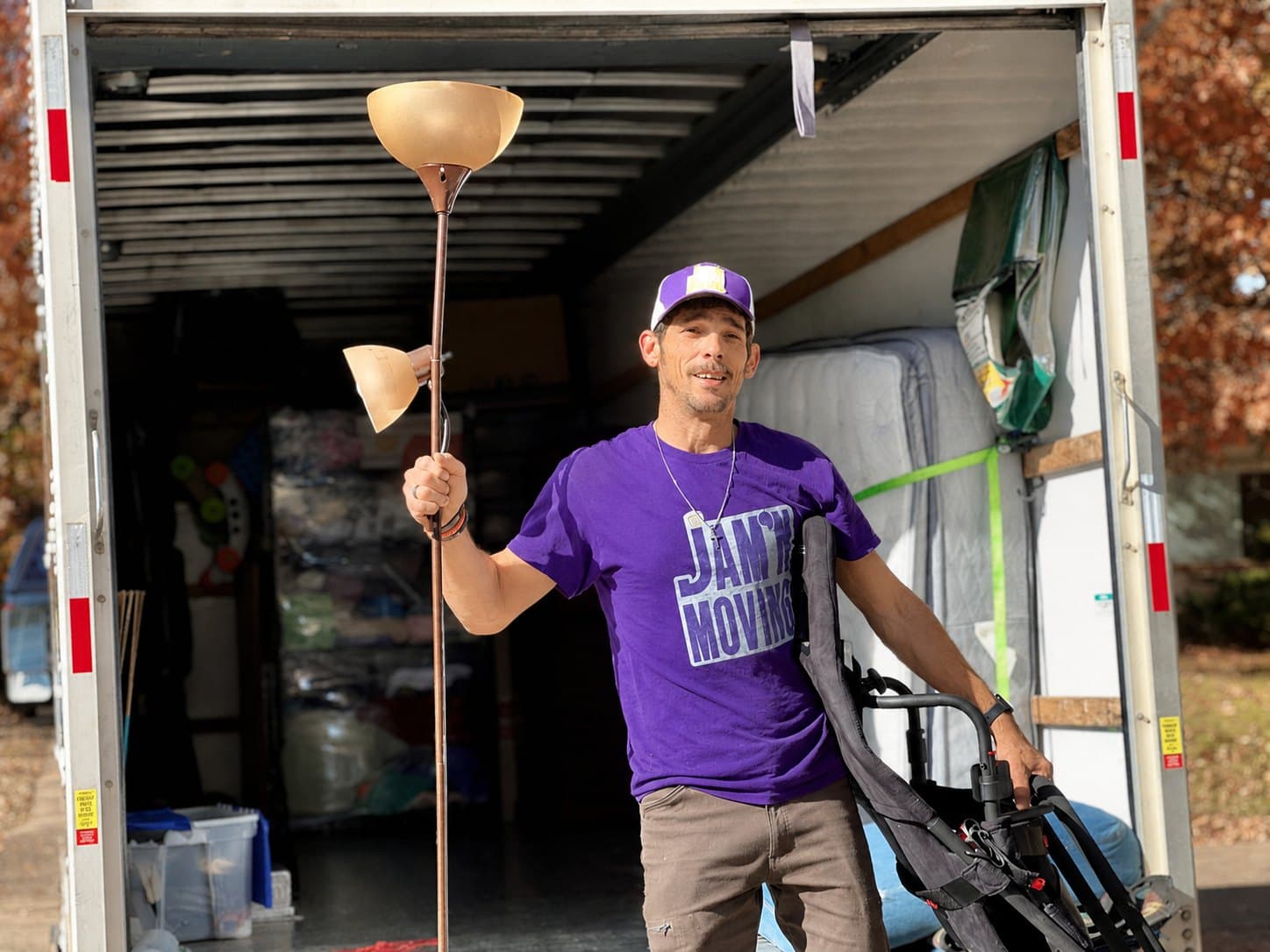 Chris Coots, owner of Jam'N Moving, unloading a lamp and hand truck from a loaded moving truck