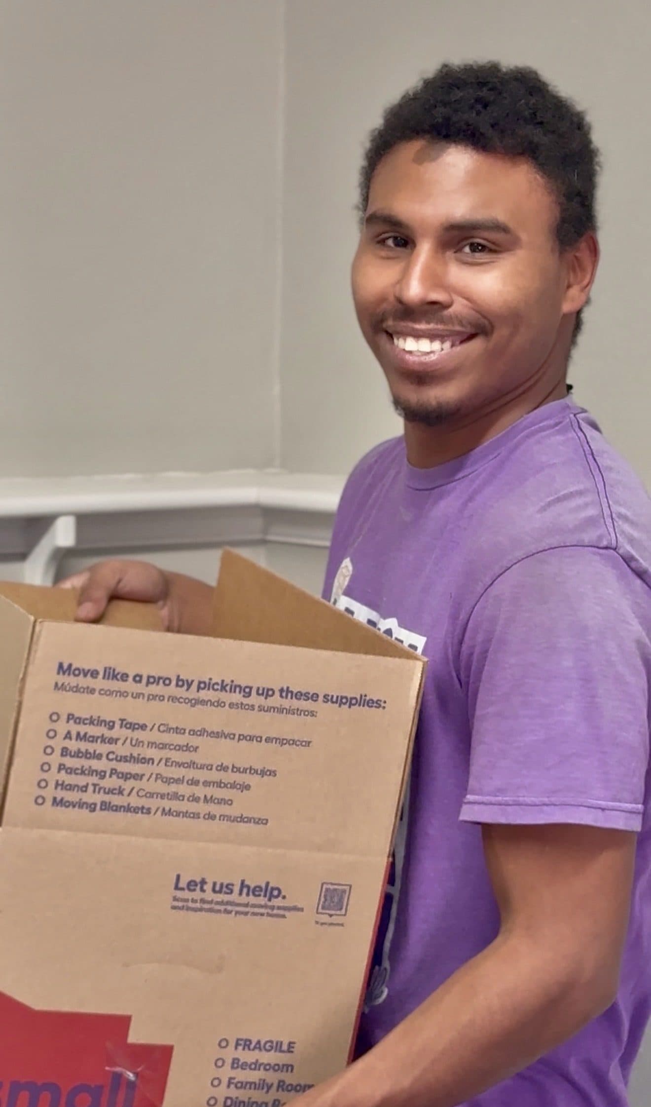A Jam'N Moving crew member carrying a moving carton