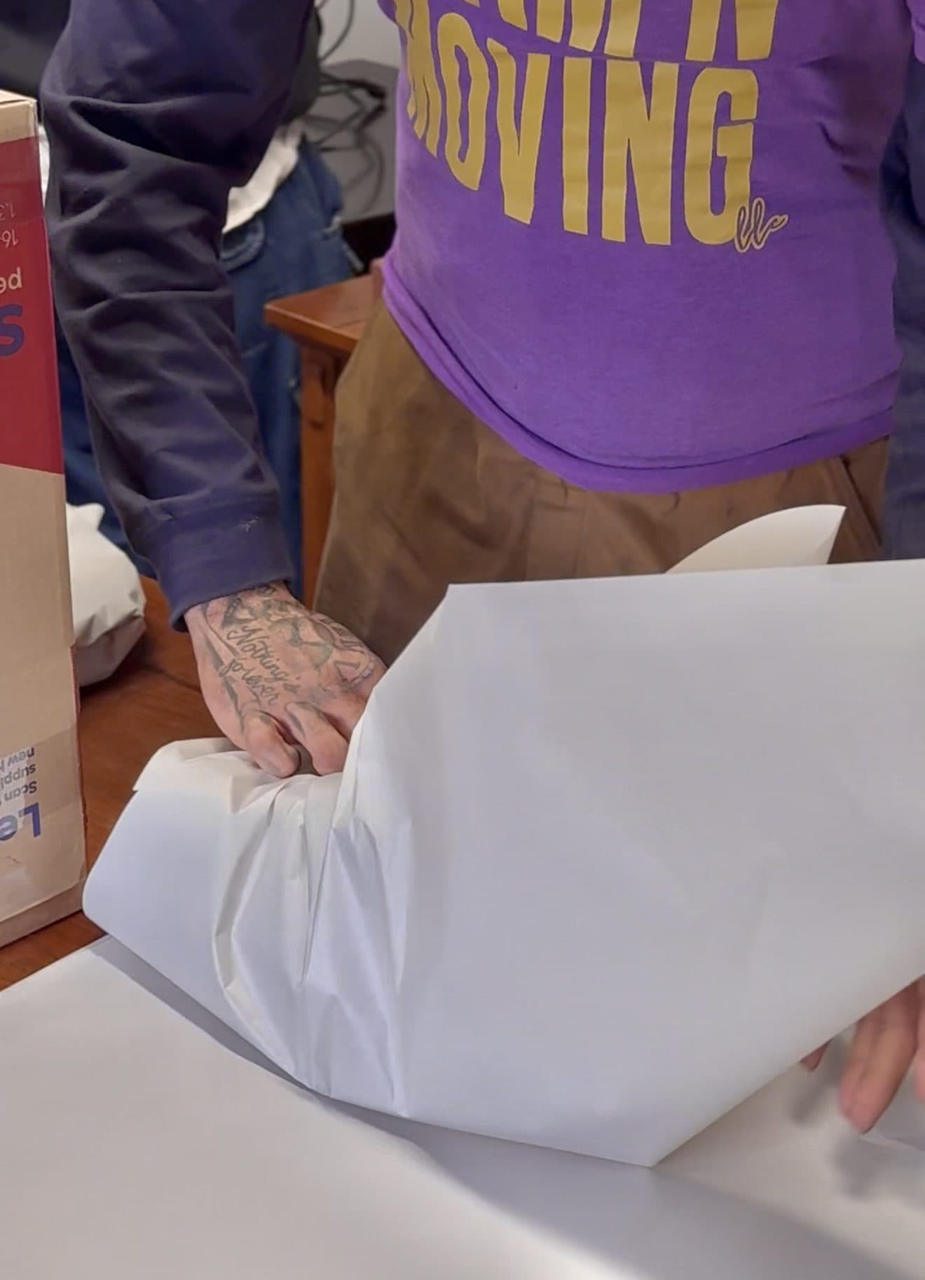 A Jam'N Moving crew member in a branded shirt wrapping a fragile item in packing paper